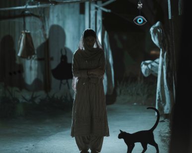 A girl standing in a street at night time.